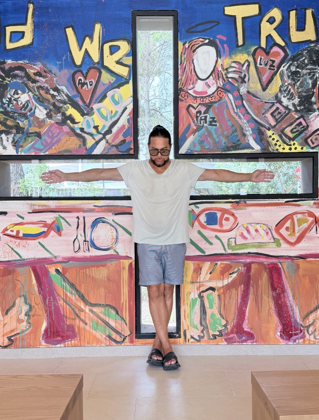Joaquín Cortés with open arms in front of a colourful mural