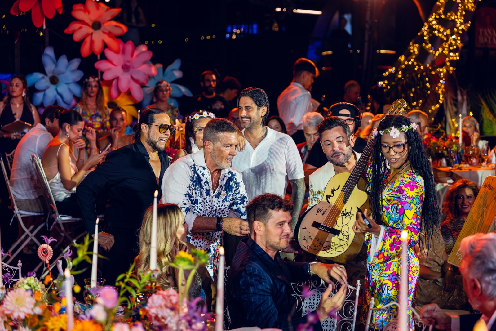 The signed guitar passing between the tables at the Gala Starlite Occident, with Antonio Banderas and Michael Bublé around it